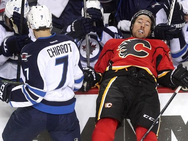 Calgary Flames right winger David Jones was driven into the Winnipeg Jets bench by defenceman Ben Chiarot during first period NHL action at the Scotiabank Saddledome on October 3, 2015.