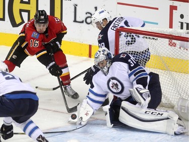Calgary Flames right winger Josh Jooris tried to tip the puck past Winnipeg Jets goalie Ondrej Pavelec while defenceman Toby Enstrom tried to stop Jooris during second period NHL action at the Scotiabank Saddledome on October 3, 2015.