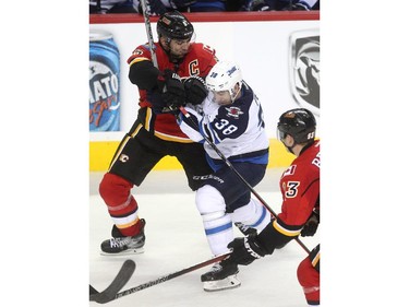 Calgary Flames defenceman Mark Giordano tied Winnipeg Jets left winger Nic Petan before sending him crashing to the ice during second period NHL action at the Scotiabank Saddledome on October 3, 2015. Giordano received an interferance call on the play.