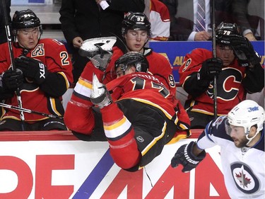 Calgary Flames players, from left, right winger Jiri Hudler, centre Sam Bennett and left winger Micheal Ferland reacted on the bench after Winnipeg Jets right winger Anthony Peluso sent Flames left winger Lance Bouma into the bench during second period NHL action at the Scotiabank Saddledome on October 3, 2015.