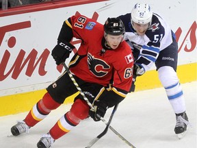 Calgary Flames defenceman Brett Kulak skated against Winnipeg Jets centre Andrew Copp during second period NHL action at the Scotiabank Saddledome on October 3, 2015.