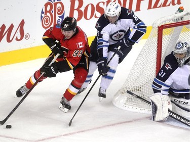 Calgary Flames centre Sam Bennett rounded the Winnipeg Jets net and was followed Jets defenceman Jacob Trouba as goalie Ondrej Pavelec watched during third period NHL action at the Scotiabank Saddledome on October 3, 2015. The Jets defeated the Flames 3-2.