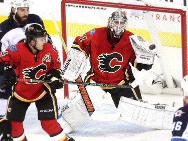 Calgary Flames goalie Karri Ramo kept his eye on a shot by the Winnipeg Jets as teammate Kris Russell kept Jets left winger Chris Thorburn at bay during first period NHL action at the Scotiabank Saddledome on October 3, 2015.