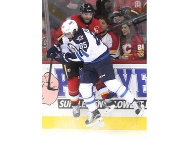 Calgary Flames defenceman Mark Giordano was driven into the boards by Winnipeg Jets left winger Mathieu Perreault during first period NHL action at the Scotiabank Saddledome on October 3, 2015.