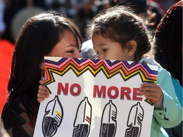Wynter Ducharme and her daughter Rayne hold a placard as they listen during the Sisters In Spirit ceremony for missing and murdered aboriginal women Monday October 5, 2015 at City Hall. Dozens walked from City Hall to Eau Claire in the 11th annual march and ceremony.