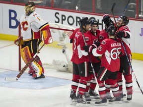 Calgary Flames goalie Jonas Hiller stands in his crease as Ottawa Senators right winger Bobby Ryan (6) celebrates his goal with teammates Marc Methot (3), Kyle Turris (7), Mark Stone (61) and Erik Karlsson (65) during second period NHL action Wednesday in Ottawa.