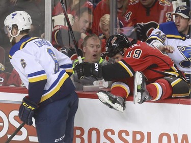 Calgary Flames David Jones gets checked into the St. Louis Blues' bench by Joel Edmundson during game action at the Saddledome in Calgary, on October 13, 2015.