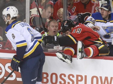 Calgary Flames David Jones gets checked into the St. Louis Blues' bench by Joel Edmundson during game action at the Saddledome in Calgary, on October 13, 2015.