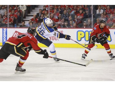 Calgary Flames Kris Russell, left, and Dennis Wideman try to stop St. Louis Blues Troy Brouwer's shot on net during game action at the Saddledome in Calgary, on October 13, 2015.