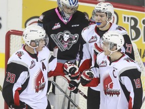 Calgary Hitmen goalie Lasse Petersen hangs his head as Moose Jaw Warriors Dryden Hunt, left, Tanner Faith and captain Brayden Point of Calgary, right, celebrate one of 10 goals in a rout at the Scotiabank Saddledome on Thursday night.