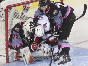Calgary Hitmen's Beck Malenstyn helps his goaltender Kyle Dumba keep Moose Jaw Warriors' Jesse Shynkaruk from scoring during game action at the Saddledome in Calgary, on October 15, 2015.