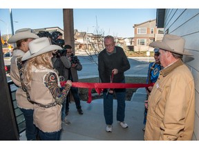 Paul Allred cuts the ribbon during a ceremony where he received keys to this year's Calgary Stampede Rotary Dream Home by Homes by Avi in Walden.