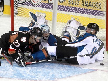 Hitmen Taylor Sanheim ends up in the net with Ice goalie Wyatt Hoflin and Mario Grman while teammate Noah Philp skates in, in the second period as the Calgary Hitmen hosted the Kootenay Ice in their WHL home opener at the Saddledome.