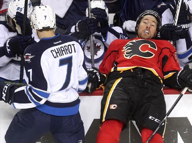 Calgary Flames right winger David Jones was driven into the Winnipeg Jets bench by defenceman Ben Chiarot during first period NHL action at the Scotiabank Saddledome on October 3, 2015.