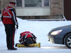 Calgary police look under vehicles for signs of a collision at a road block Wednesday morning, near the spot where pedestrian Wong Shuk Yee was killed after being hit by two vehicles last week. Charges have been laid against one driver, but police are still searching for the second. Members of the local community attended a rally promoting traffic safety awareness at the intersection of Sandstone Drive and Berkshire Blvd N.W. in Calgary, Alberta Wednesday, February 27, 2013.