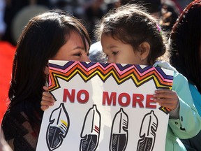 Wynter Ducharme and her daughter Rayne hold a placard as they listen during the Sisters in Spirit ceremony for missing and murdered aboriginal women Monday, Oct. 5 at City Hall. Dozens walked from City Hall to Eau Claire in the 11th annual march and ceremony.