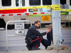 A police officer comforts a witness at the scene of a fatal CTrain collision near Rundle Station in northeast Calgary on October 22, 2015.