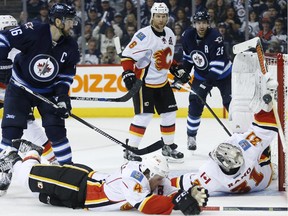 Calgary Flames' Kris Russell, bottom centre, (4) goes down to block the shot as goaltender Karri Ramo, right, saves it while teammate Dennis Wideman (6), Winnipeg Jets' Andrew Ladd, left, and Blake Wheeler (26) look on during second period NHL action in Winnipeg on Friday, Oct. 16, 2015.