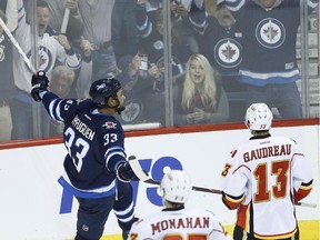 Winnipeg Jets defenceman Dustin Byfuglien celebrates his game-winning goal as Calgary Flames' Sean Monahan and John Gaudreau, right, look on during the third period in Winnipeg on Friday.