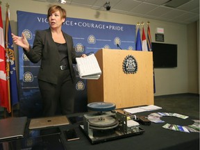 Staff Sgt. Kristie Verheul with the economic crimes unit shows off forged credit cards, a replica handgun, an embossing machine, a variety of computers and mobile devices, and a notebook containing credit card numbers at Calgary Police Headquarters in Calgary on Thursday, Nov. 12, 2015. The items were seized in a recent operation.