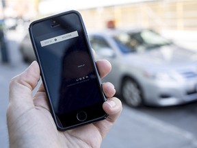 The Uber app is photographed with taxis in the background on Dalhousie St. in Ottawa on Thursday, Sept. 11, 2014.