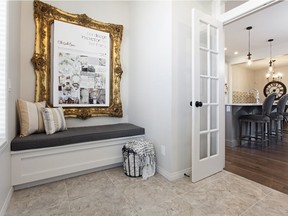 The front foyer includes a bench to sit on one side and a closet opposite, with french doors separating the space from the main home in the Triumph model rear-attached garage show home by Hopewell Residential in Mahogany.