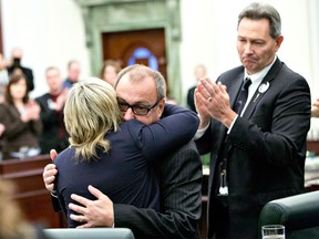 Conservative MLA Ric McIver is hugged by fellow MLA Sandra Jansen as MLA Richard Starke applauds during a tribute to Manmeet Bhullar at the Alberta Legislature chambers in Edmonton on Wednesday, Nov. 25, 2015. Bhullar, 35, was killed in a car accident on Monday afternoon while driving from Calgary to Edmonton.