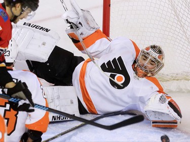 Calgary Flames forward Michael Frolic tries to get this loose puck past Philadelphia Flyers goaltender Michal Neuvirth during the first period of NHL action at the Scotiabank Saddledome on Thursday Nov. 5, 2015