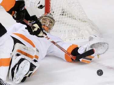 Philadelphia Flyers goaltender Michal Neuvirth goes down on his back as he stretches to reach the puck during the first period of NHL action at the Scotiabank Saddledome on Thursday Nov. 5, 2015