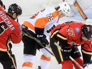 The Philadelphia Flyers' Ryan White is wedged between Dennis Wideman and Derek Grant during the third period of NHL action at the Scotiabank Saddledome on Thursday Nov. 5, 2015