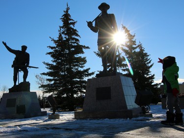 A young Remembrance Day visitor looks up at statues honouring World War I and Second World War soldiers at the 2015 Remembrance Day service at the Military Museums in Calgary.