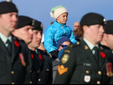 A young girl watches from her fathers shoulders as they attend the 2015 Remembrance Day service at the Military Museums in Calgary.