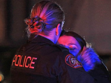 A police officer comforts a distraught woman at a fatal shooting in a strip mall at 20th avenue and 52nd street S.E. on Saturday night November 14, 2015.