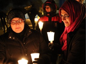 Aliya Adnan, left, and Humera Abbas take part in a candlelight vigil in front of the Calgary City Hall organized by the Muslim Council of Calgary to show solidarity with the victims of the Paris attack.