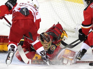 Calgary Flames goalie Jonas Hiller stretched to stop the puck as Detroit Red Wings left winger Teemu Pulkkinen searched for a rebound during third period NHL action at the Scotiabank Saddledome on October 23, 2015.