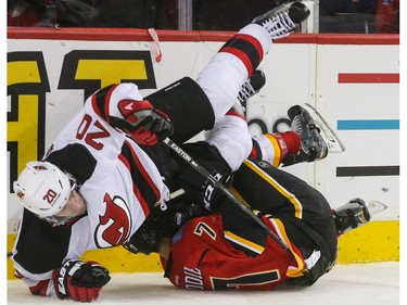 Calgary Flames defenceman TJ Brodie, bottom, sends New Jersey Devils right winger Lee Stempniak flying at the Scotiabank Saddledome in Calgary on Tuesday, November 17, 2015. The Flames won over the New Jersey Devils, 3-2, in regular season play.