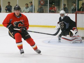 Michael Ferland, left, takes off towards the boards to collect a puck during Calgary Flames practice at WinSport in Calgary on Sunday, Sept. 20, 2015.
