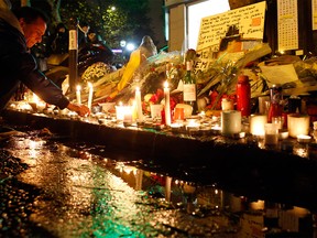 A man lights candles outside La Belle Equipe restaurant in Paris, Tuesday, Nov. 17, 2015, one of the spots of Friday's attacks.
