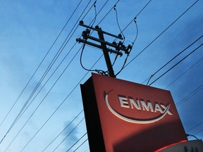 Powerlines rise behind an Enmax sign at the company's head office in Calgary.