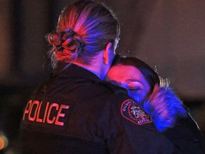 Gavin Young, Calgary Herald CALGARY, AB: NOVEMBER 14, 2015 - A police officer comforts a distraught woman at a fatal shooting in a strip mall at 20th avenue and 52nd street S.E. on Saturday night November 14, 2015. (Gavin Young/Calgary Herald) (For City section story by Erika Stark) Trax#