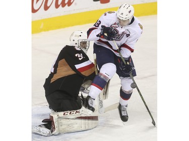 Regina Pats Aaron Macklin tries to screen Calgary Hitmen goalie Cody Porter and poke in the rebound during game action at the Saddledome in Calgary, on November 27, 2015.