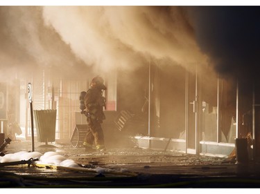 A fire fighter looks into the Billingsgate Seafood Market as members of the Calgary Fire Department worked to extinguish a two alarm fire at the Stadium Shopping Centre on Nov. 12, 2015.