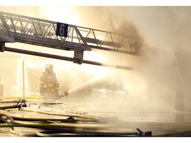 A member of the Calgary Fire Department sprayed water into the Billingsgate Seafood Market as firefighters worked to extinguish a two alarm fire at the Stadium Shopping Centre on Nov. 12, 2015.