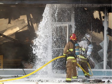 Members of the Calgary Fire Department worked to douse hot spots after the roof collapsed in the Billingsgate Seafood Market during a two alarm fire at the Stadium Shopping Centre on November 12, 2015. At least four businesses were heavily damaged by fire while others in the mall sustained smoke and water damage.