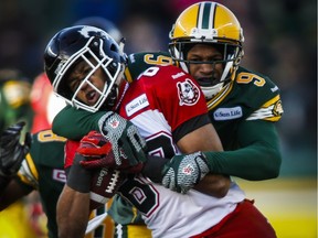 Calgary Stampeders receiver Eric Rogers, left, is tackled by Edmonton Eskimos' Patrick Watkins during the first half of the CFL West Division final in Edmonton on Sunday.