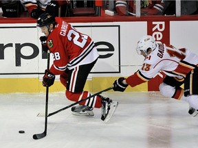 Chicago Blackhawks' Ryan Garbutt (28) moves the puck against Calgary Flames' Johnny Gaudreau (13) during the first period on Sunday. Gaudreau was skating in his 100th NHL game.