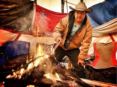 Ben Crow Chief stokes a fire inside his teepee he is living in on the Siksika First Nation to block access to a housing construction site.