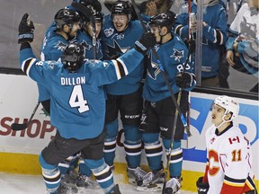 San Jose Sharks' Tomas Hertl, second from right, celebrates with teammates after scoring against the Calgary Flames during the first period of an NHL hockey game, Saturday, Nov. 28, 2015, in San Jose, Calif. In the foreground is Flames' Mikael Backlund (11).
