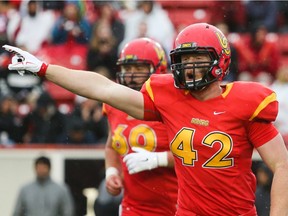 Dinos player Micah Teitz, centre, lets out a cheer after a successful play at McMahon Stadium in Calgary on Friday, Sept. 4, 2015.