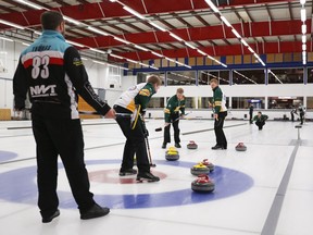 Charley Thomas, left, watches Team Scoffin work on a rock during the World Curling Tour's Original 16 final at the Calgary Curling Club on Sunday. Team Thomas rolled to a dominant 6-2 win.